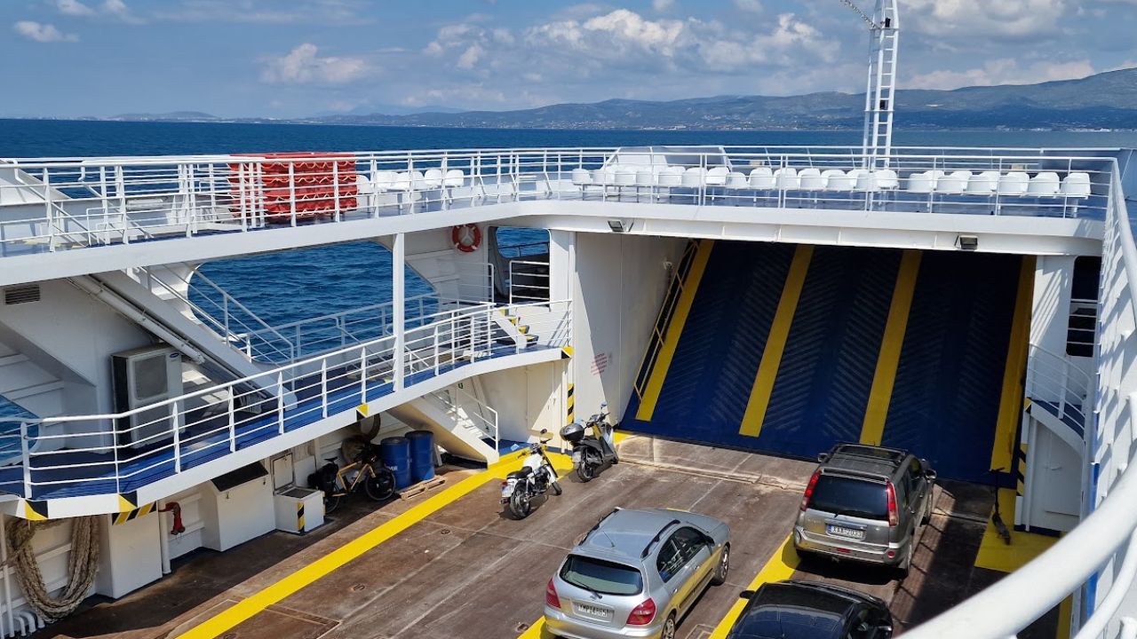 vehicle deck of the Oropos to Eretria ferry with cars and motorbikes, upper deck seating above and hills across the water
